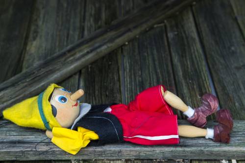 Wooden Pinocchio puppet splayed out on a bench